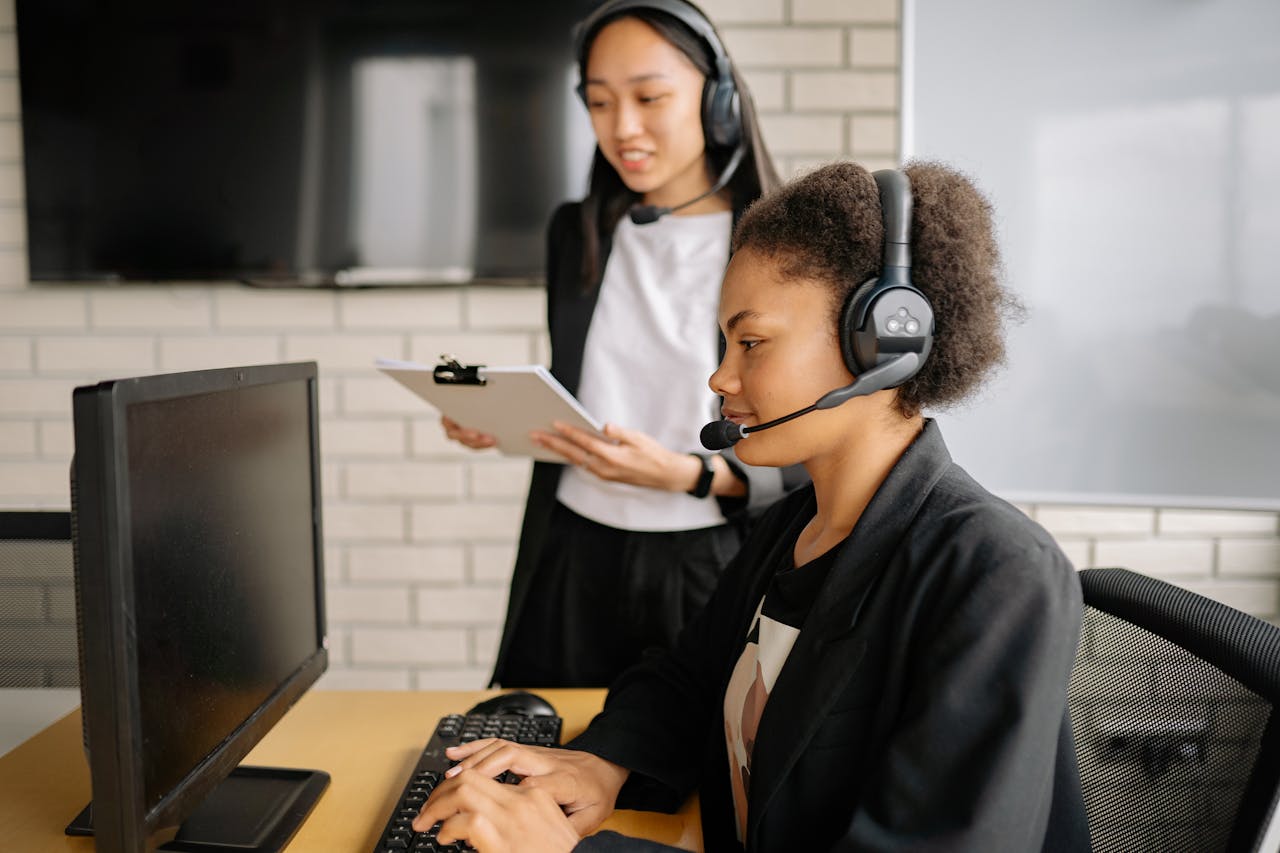 Two professional women working in a call center, focused on customer support in a modern office environment.